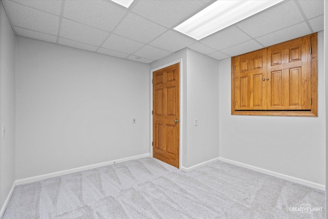 empty room with a paneled ceiling, carpet floors, and baseboards