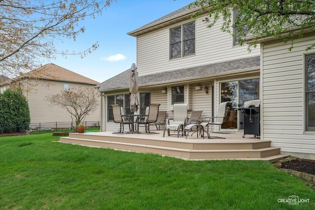 rear view of property featuring fence, a yard, and a shingled roof