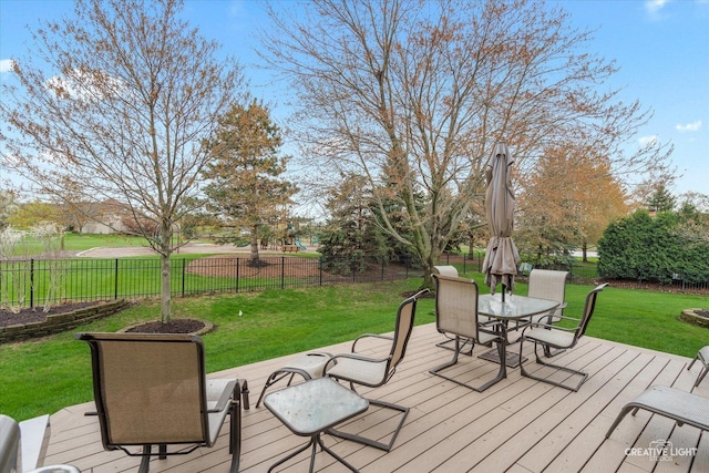 deck featuring fence, outdoor dining area, and a lawn