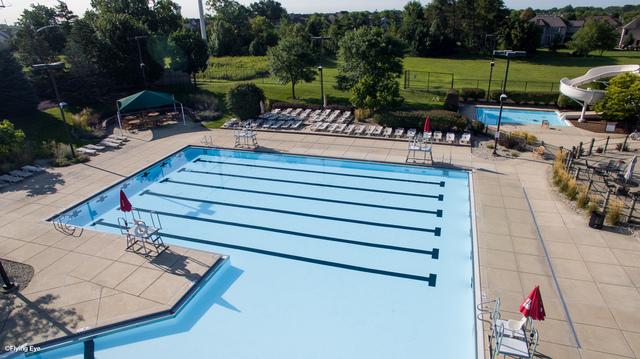 community pool with a water slide, a patio, and fence