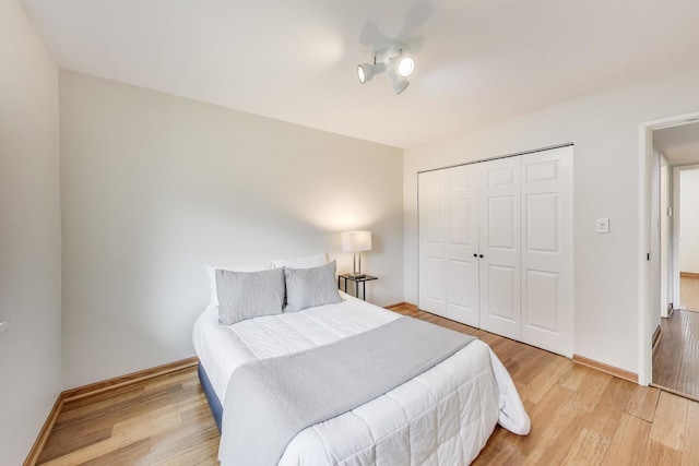 bedroom featuring baseboards, light wood-style floors, and a closet