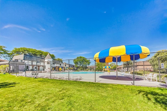 view of swimming pool featuring a lawn and fence