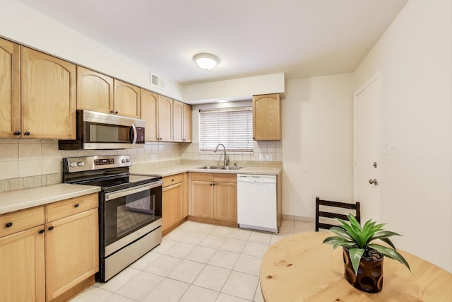 kitchen featuring visible vents, light brown cabinetry, stainless steel appliances, and a sink