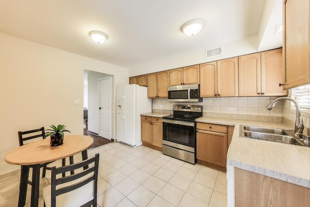 kitchen featuring light countertops, visible vents, a sink, tasteful backsplash, and appliances with stainless steel finishes