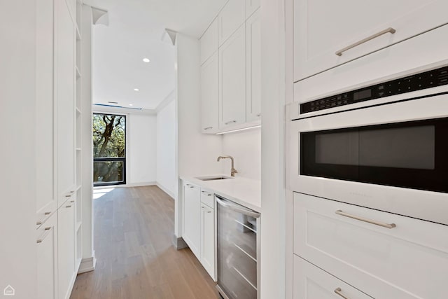1646 N Orchard St Unit 3S, Chicago, IL 60614 - kitchen featuring beverage cooler, a sink, light wood finished floors, white cabinets, and light countertops
