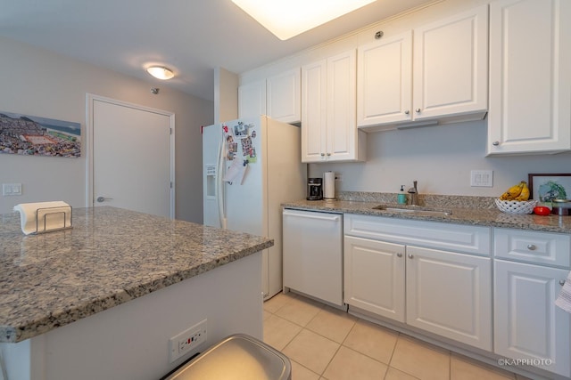 kitchen with light tile patterned floors, white cabinets, a sink, white appliances, and light stone counters
