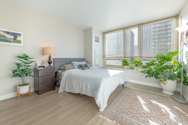 bedroom featuring visible vents, baseboards, and light wood-style floors
