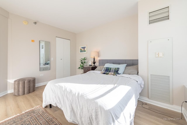 bedroom with light wood-type flooring, a closet, baseboards, and visible vents