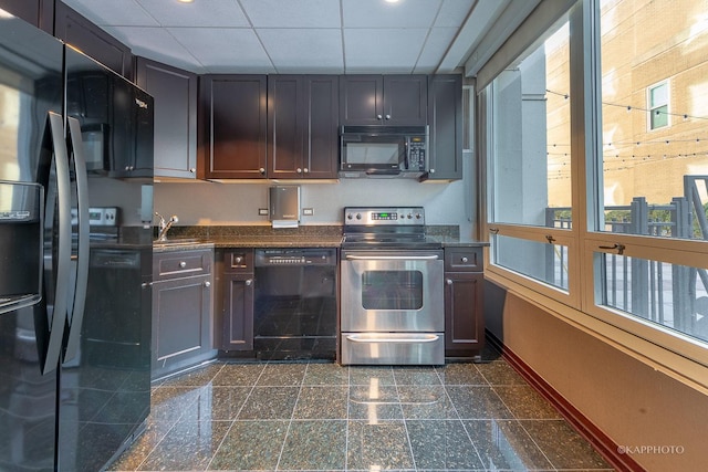 kitchen featuring granite finish floor, dark countertops, black appliances, a drop ceiling, and a sink