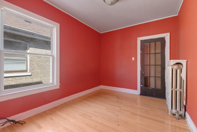 spare room featuring crown molding, baseboards, and light wood-type flooring
