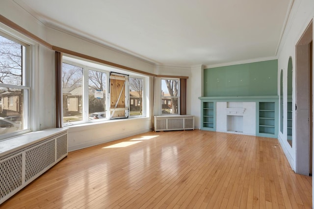 unfurnished living room with crown molding, radiator heating unit, a fireplace, and hardwood / wood-style flooring