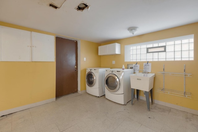 laundry room with cabinet space, baseboards, washer and dryer, and light floors