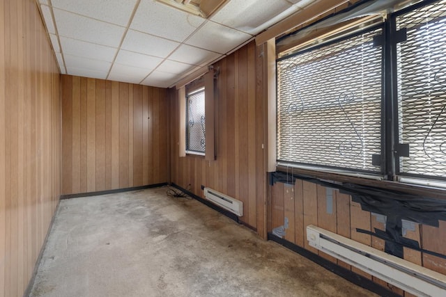 spare room featuring wooden walls, a paneled ceiling, and a baseboard radiator