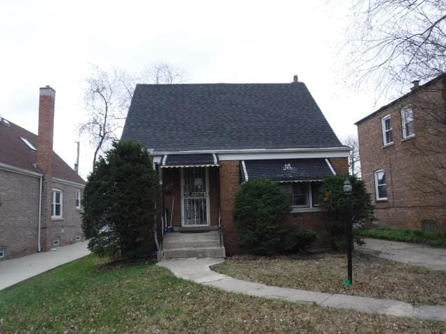 view of front of home with brick siding and roof with shingles