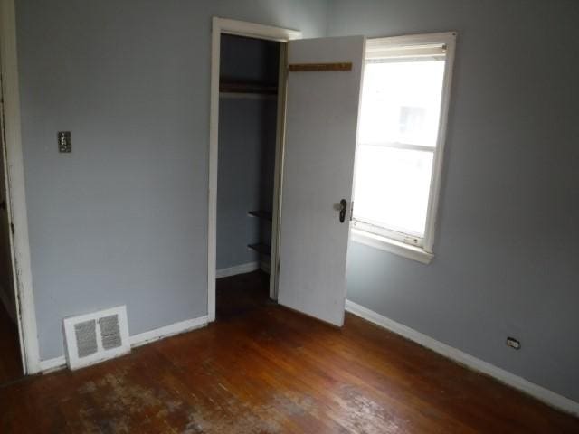 unfurnished bedroom featuring baseboards, visible vents, wood finished floors, and a closet