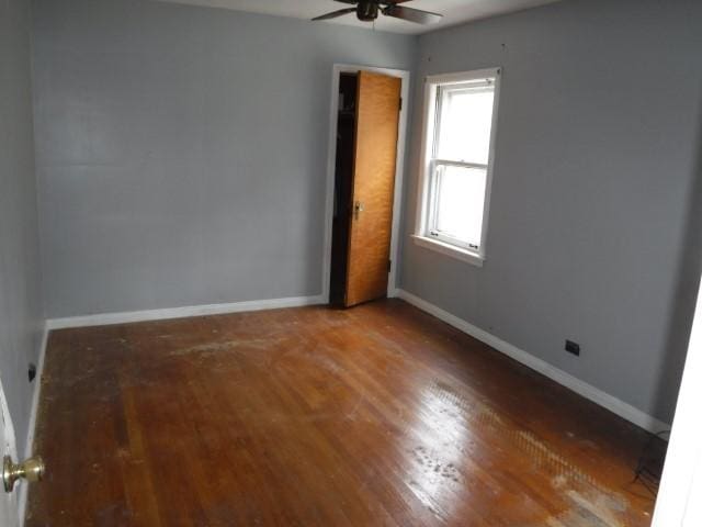 spare room featuring a ceiling fan, baseboards, and wood finished floors