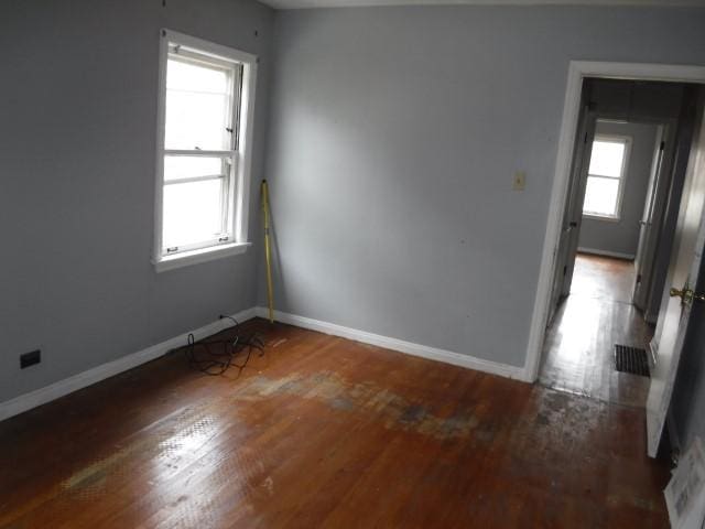spare room featuring baseboards, plenty of natural light, and wood finished floors