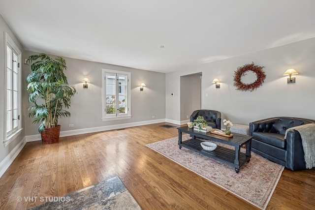 living area with baseboards, wood finished floors, and visible vents