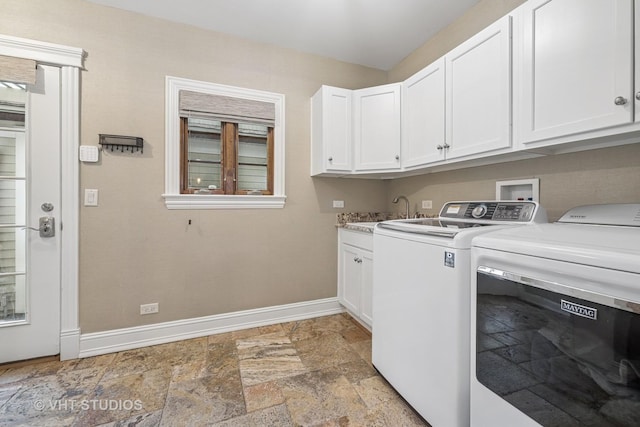 clothes washing area with a sink, baseboards, stone tile floors, and washing machine and clothes dryer