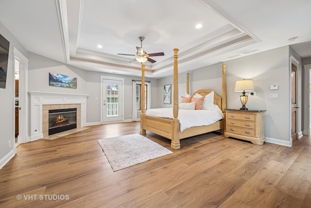 bedroom with recessed lighting, a tray ceiling, ornamental molding, and light wood-style flooring
