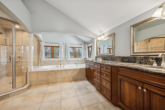 full bathroom with double vanity, a bath, a shower stall, a sink, and vaulted ceiling