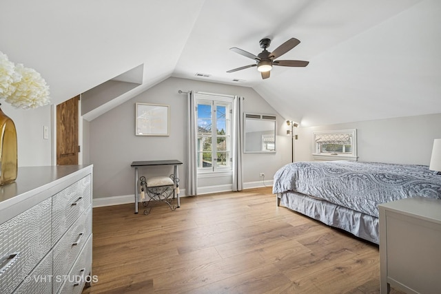 bedroom with a ceiling fan, visible vents, wood finished floors, baseboards, and lofted ceiling