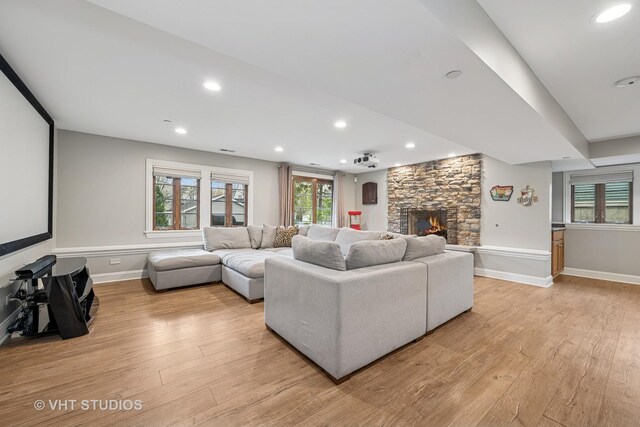 living room featuring a fireplace, baseboards, and light wood-style floors