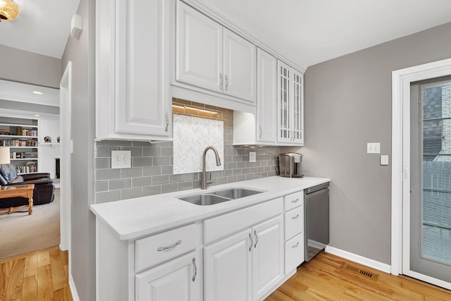 6650 Powell St, Downers Grove, IL 60516 - kitchen with glass insert cabinets, light countertops, stainless steel dishwasher, light wood finished floors, and a sink