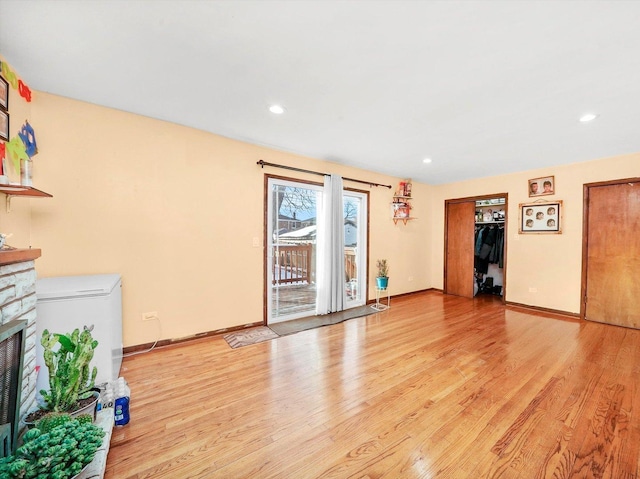 unfurnished living room with recessed lighting, a fireplace, light wood-style flooring, and baseboards
