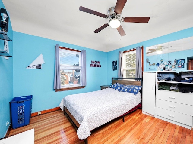 bedroom featuring baseboards, light wood finished floors, and a ceiling fan