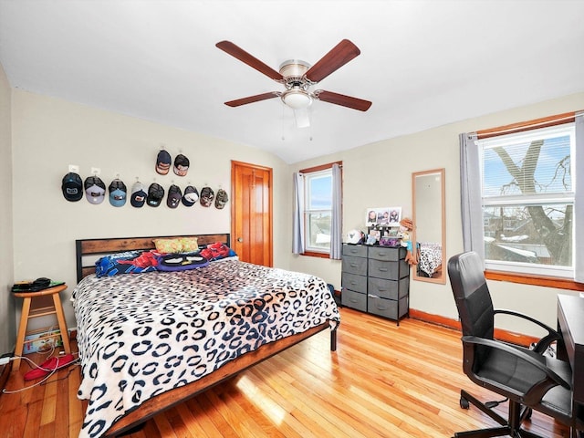 bedroom with wood finished floors, ceiling fan, baseboards, and multiple windows
