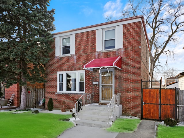 view of front of house with brick siding, a front yard, and fence