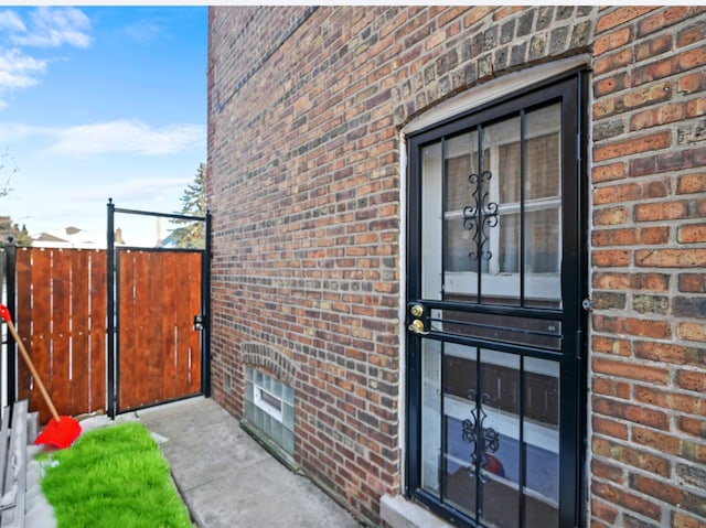 property entrance with fence and brick siding