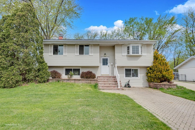 split foyer home featuring a chimney, driveway, and a front yard