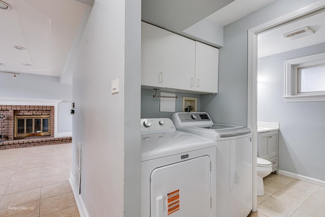 clothes washing area with baseboards, washer and clothes dryer, cabinet space, and light tile patterned floors