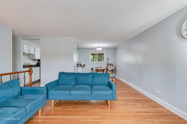 living area featuring baseboards and light wood-style flooring