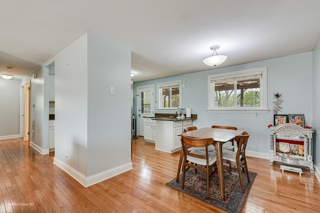 dining space with light wood-type flooring and baseboards