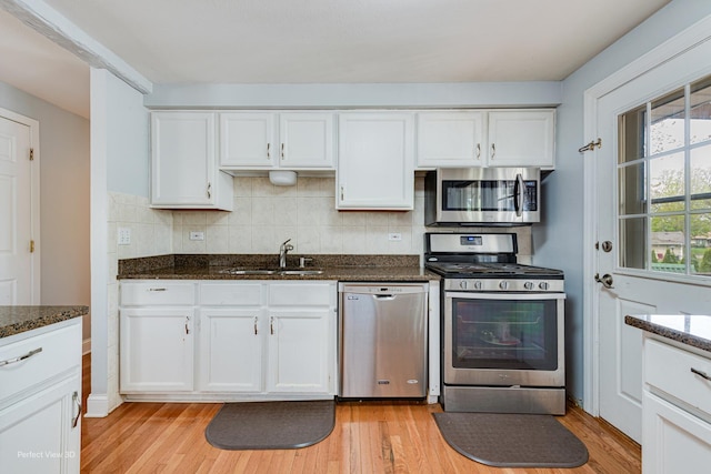 kitchen featuring a sink, appliances with stainless steel finishes, light wood finished floors, and white cabinetry