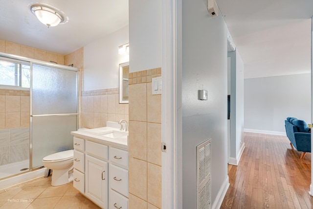 full bathroom with vanity, tile walls, toilet, and a shower stall