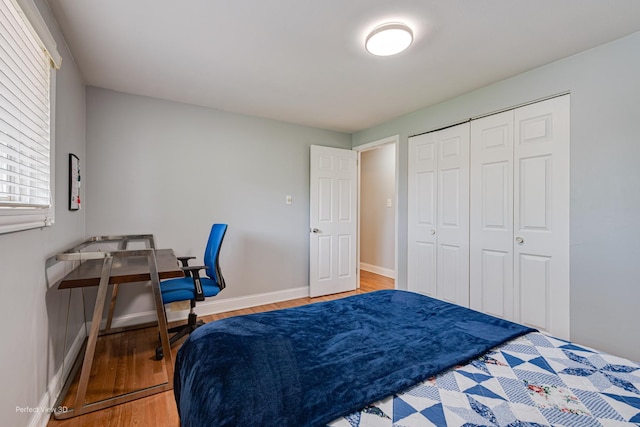 bedroom with baseboards, wood finished floors, and a closet