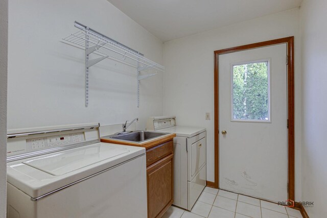 washroom with light tile patterned floors, a sink, cabinet space, and washer and clothes dryer