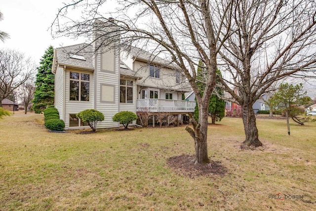 rear view of house featuring a yard, a deck, and a chimney