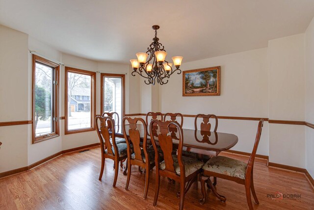 dining room with a notable chandelier, light wood-style flooring, and baseboards