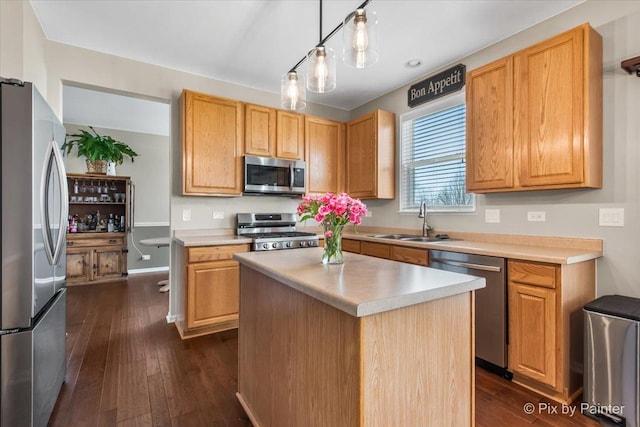 kitchen featuring dark wood-style floors, light countertops, a kitchen island, appliances with stainless steel finishes, and a sink