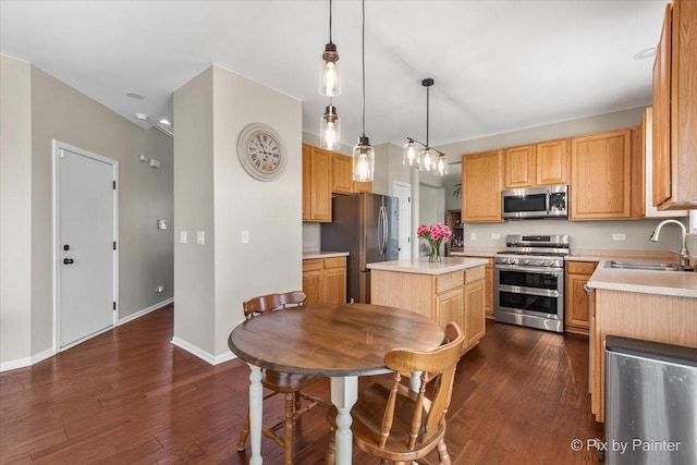 kitchen with light countertops, a kitchen island, dark wood-type flooring, stainless steel appliances, and a sink