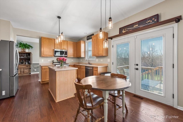 kitchen featuring visible vents, a kitchen island, appliances with stainless steel finishes, dark wood-style flooring, and light countertops