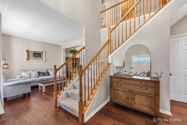 stairs with baseboards, a high ceiling, and hardwood / wood-style flooring
