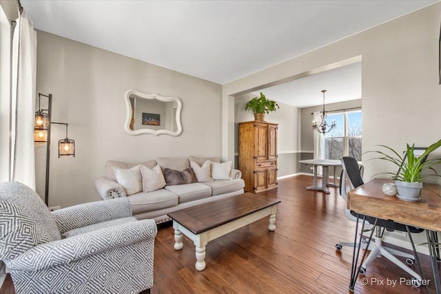 living area with baseboards, an inviting chandelier, and wood finished floors