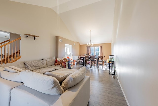 living area with baseboards, a chandelier, wood finished floors, stairs, and high vaulted ceiling