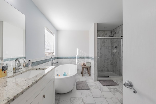 full bath with a soaking tub, a shower stall, vanity, marble finish floor, and wainscoting